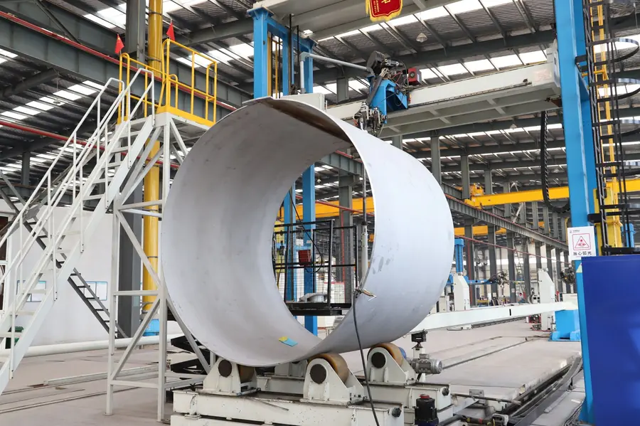 Large industrial workshop with steel pipe manufacturing equipment